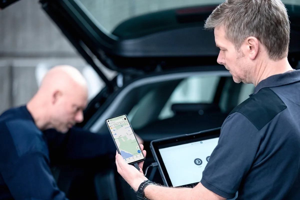 Deux policiers examinent un téléphone et une tablette près d’un véhicule