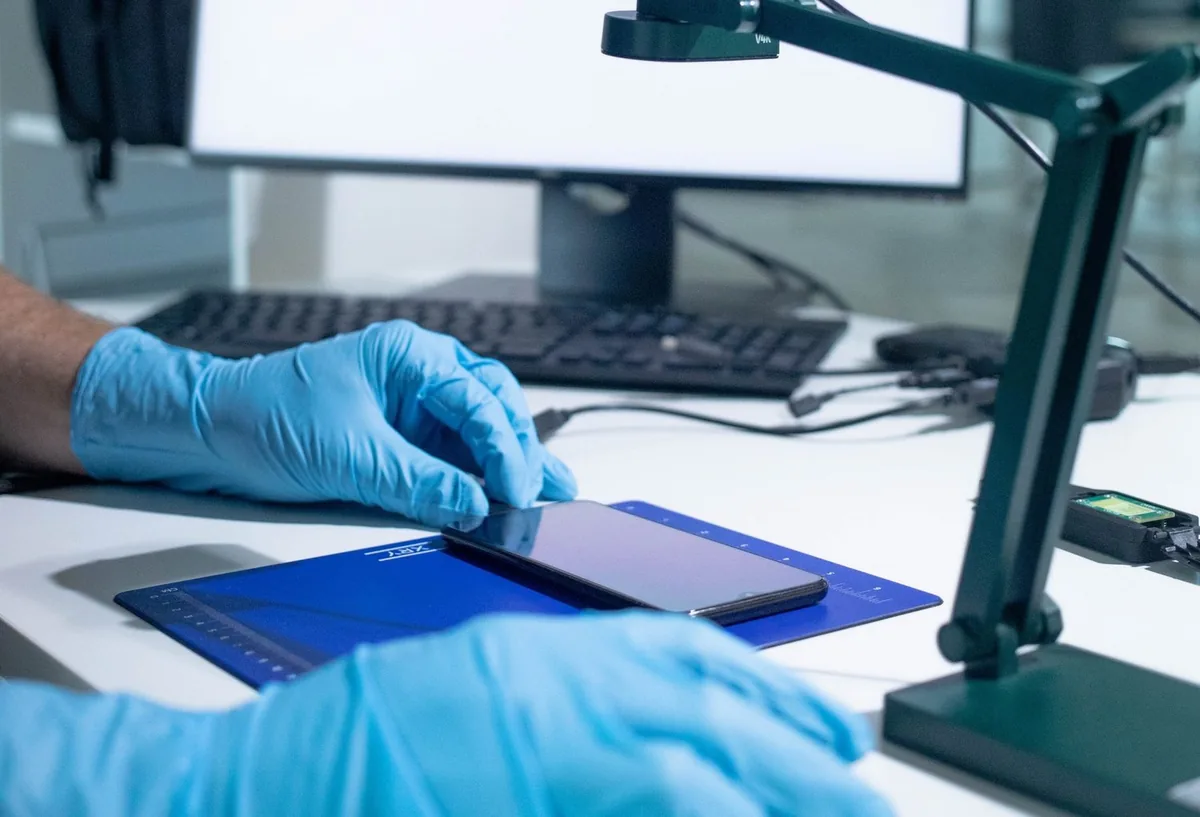 Un examinateur ganté pose une tablette sous une caméra de laboratoire