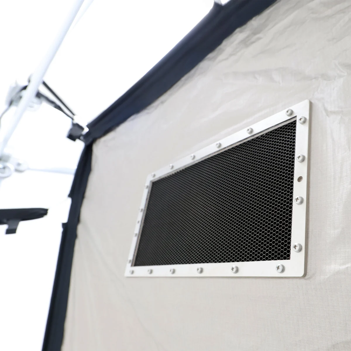 Une grille de ventilation blindée en nid d’abeille, vue depuis l’extérieur de la tente