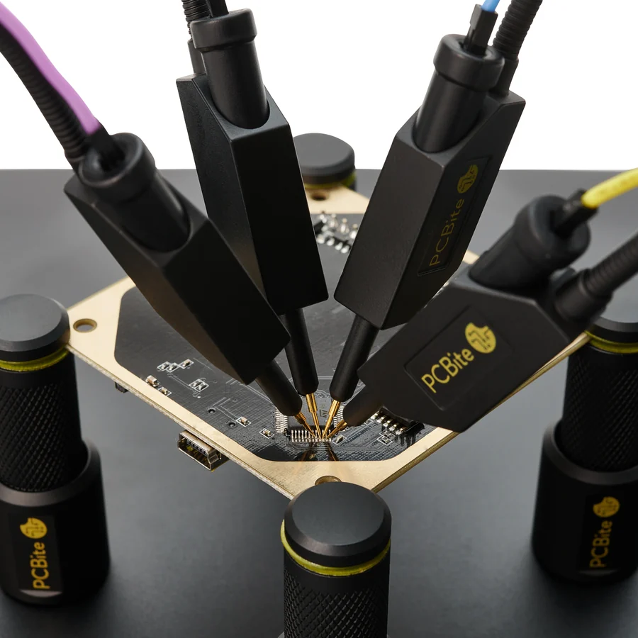 Quatre sondes PCBite posées sur les broches d’un composant d’une carte tenue par ses supports