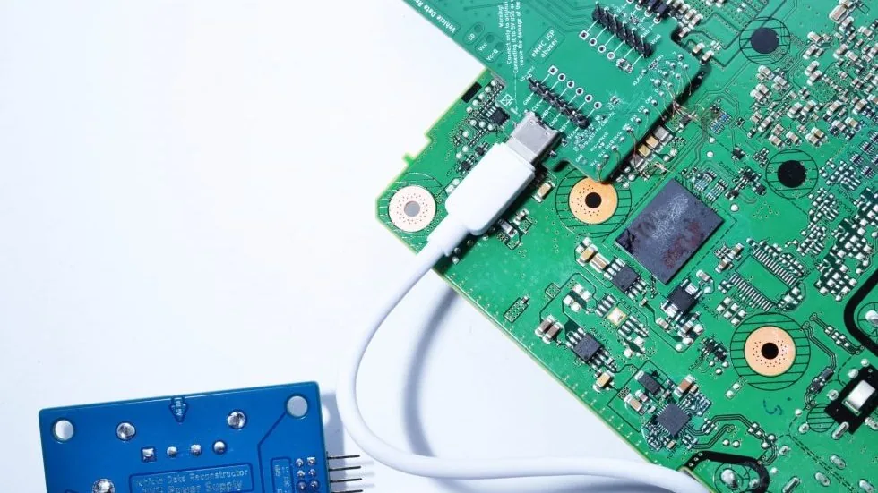 Un adaptateur ISP eMMC du VDR posé sur la carte d’un module, relié par câble USB-C